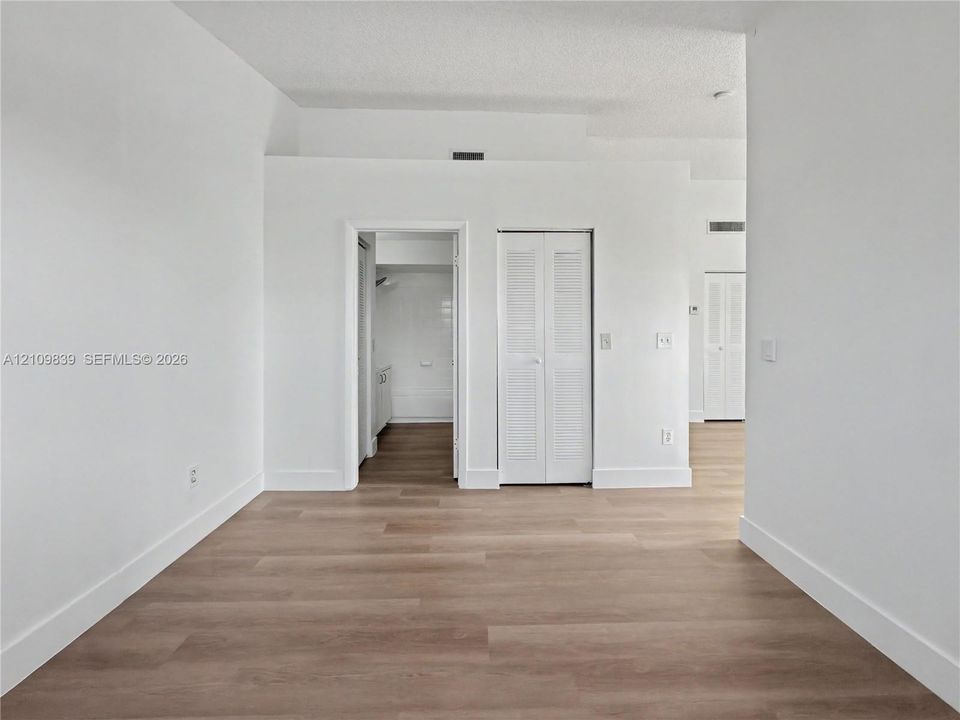 Interior space featuring light-toned wood-finish flooring, white walls, and white louvered-door closets