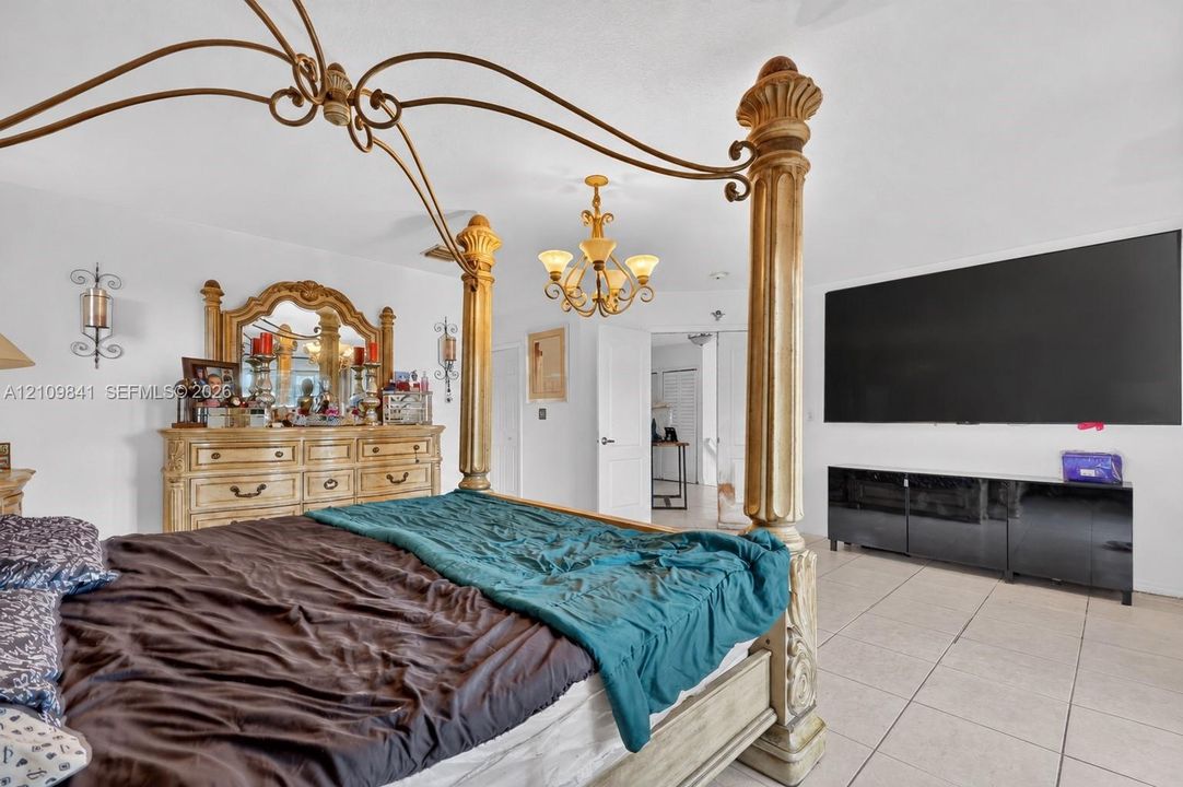 Spacious room featuring neutral tile flooring, a multi-arm metallic chandelier, and dual wall-mounted decorative sconces