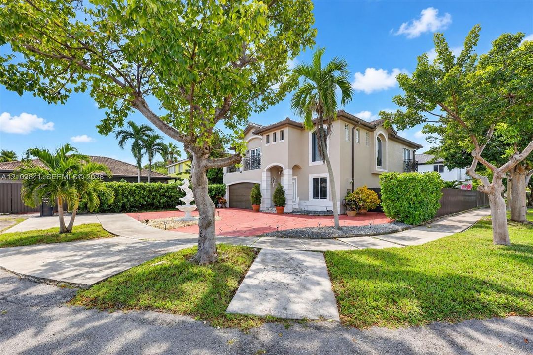 Two-story exterior featuring a stucco façade, tiled roof, attached garage, arched entry, and decorative water feature