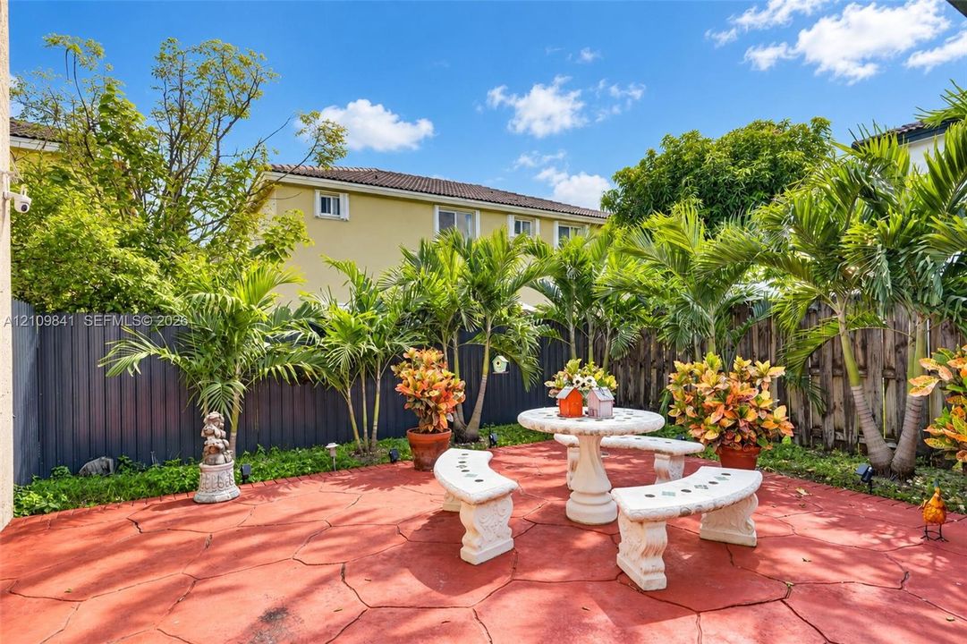 Private outdoor patio featuring stamped concrete flooring, mature palm trees, and perimeter fencing