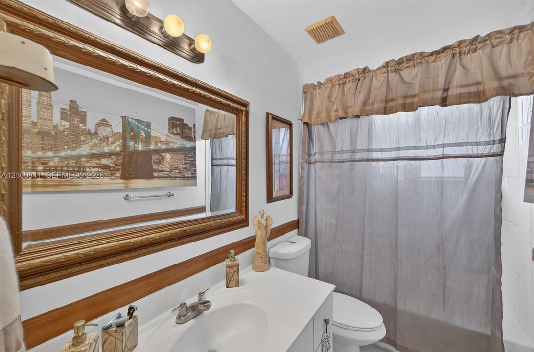 Bathroom vanity with integrated sink, polished metal faucet, wood-framed wall mirror, and three-light wall fixture