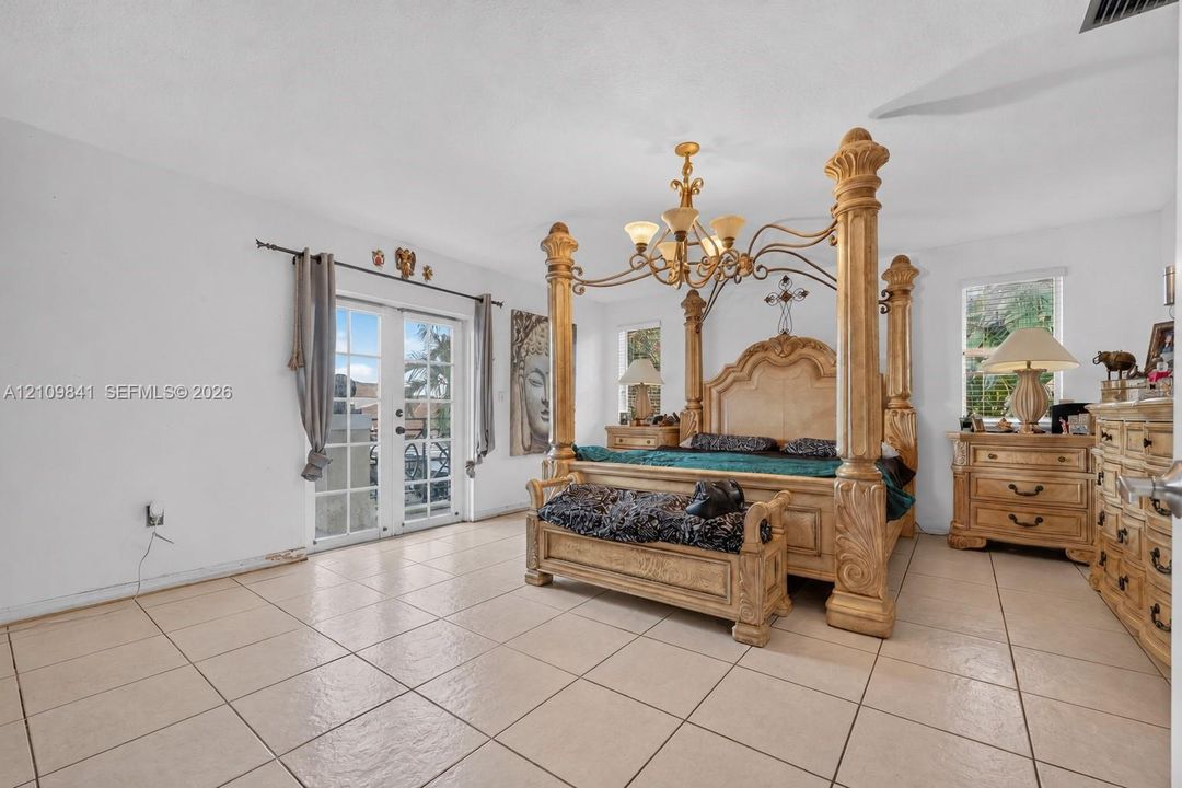Neutral-toned tile flooring, multi-light metallic chandelier, and glass-paned French doors