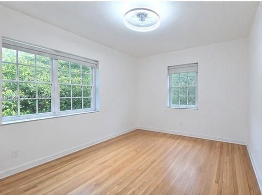 Room featuring wood-finish flooring, dual grid-pattern windows, and a flush-mount circular ceiling light fixture