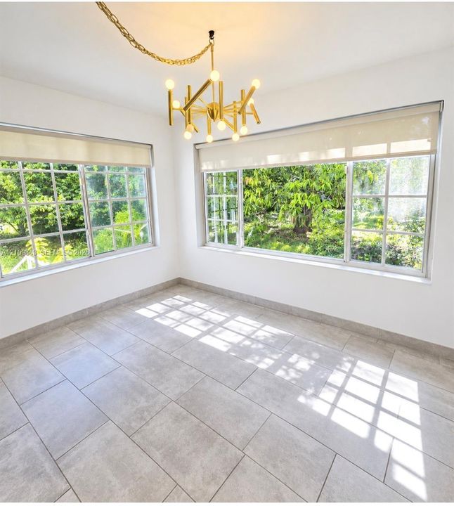 Large-format tile flooring, multi-pane windows with integrated shades, and a gold-finish multi-arm chandelier