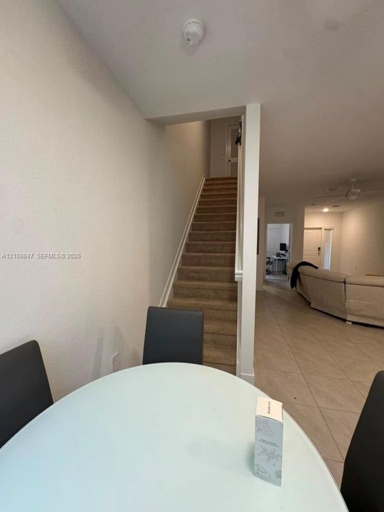 Carpeted staircase with a wooden handrail and neutral-toned tile flooring