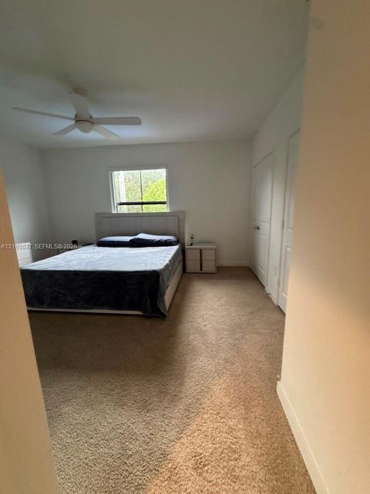 Room featuring neutral wall tones, carpeted flooring, a ceiling fan, and double-panel closet doors