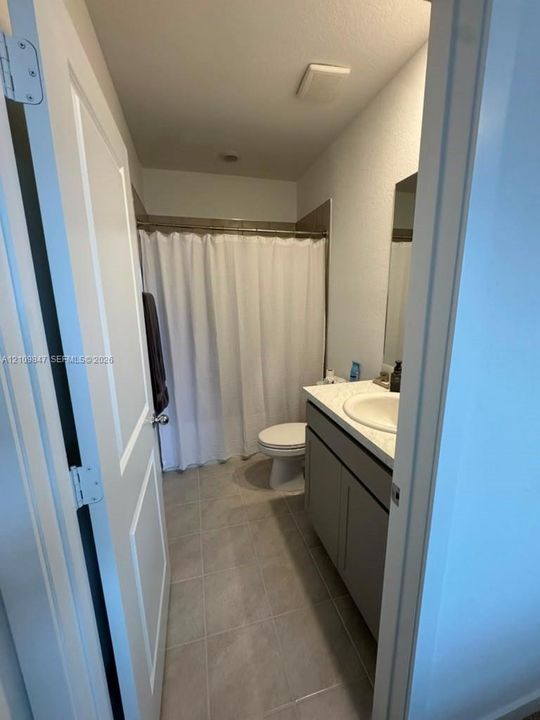 Bathroom featuring a vanity with a light-toned countertop, integrated basin, neutral-colored cabinetry, tile flooring, and a tub-shower combination