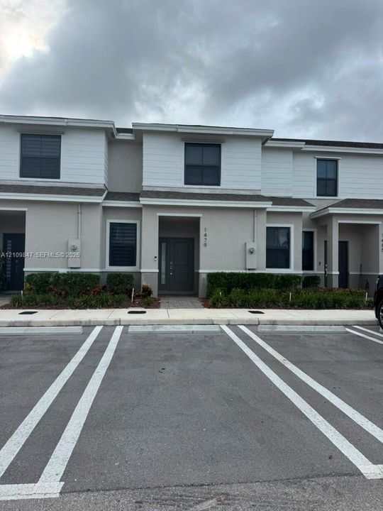 Two-story exterior featuring a neutral stucco and horizontal siding facade, dark-tinted windows, and a covered entryway