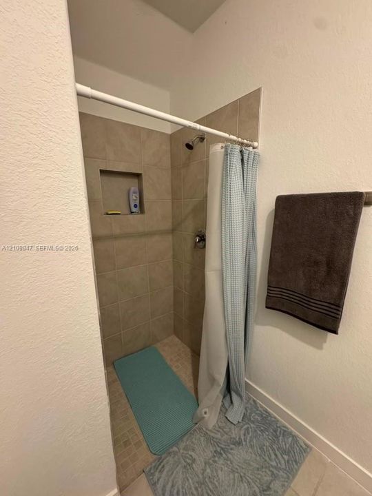 Walk-in shower featuring neutral ceramic wall tile, an integrated recessed soap niche, and a tiled shower floor