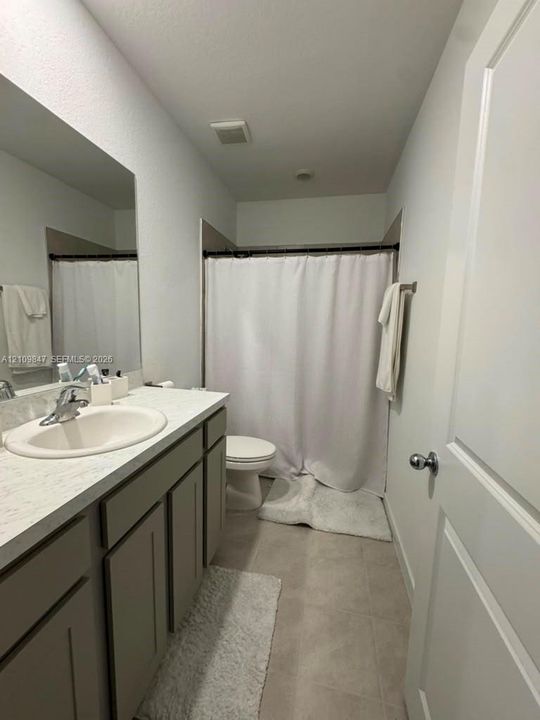 Bathroom featuring a vanity with neutral-toned cabinetry, light-colored stone-finish countertop, integrated oval basin, and large-format wall-mounted mirror