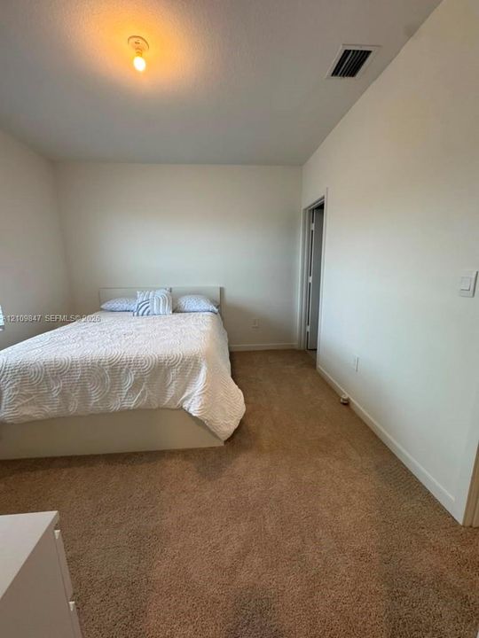 Neutral-toned wall paint, wall-to-wall carpeting, and a central ceiling-mounted light fixture