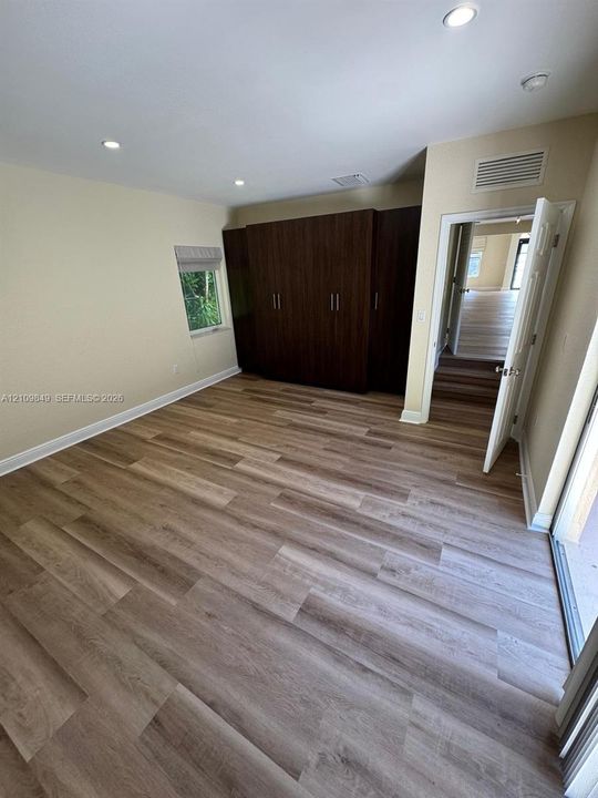Room featuring wood-finish flooring, recessed lighting, and built-in floor-to-ceiling dark wood cabinetry