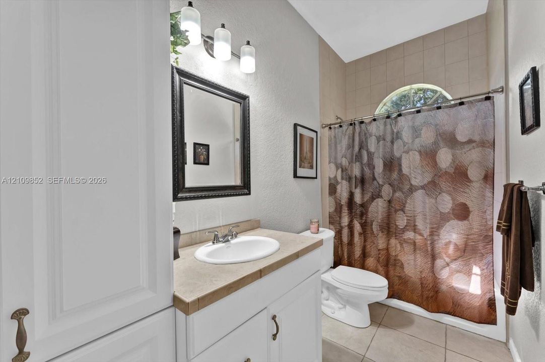 Hall bathroom featuring a shower-tub combination with a semi-circular transom window *