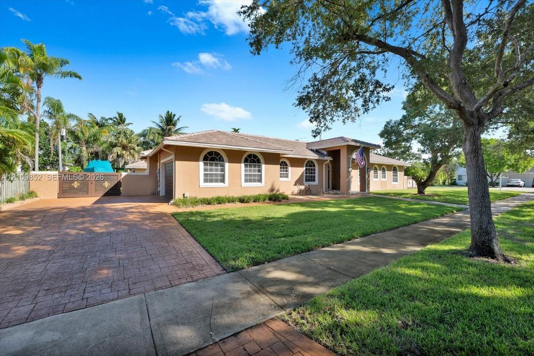 Southern exposure, arched windows, a covered entryway, a patterned concrete driveway, and mature landscaping