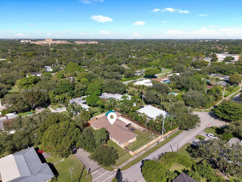 Aerial perspective of this single-story residence on a corner lot featuring a multi-hipped roof, perimeter fencing, and mature landscaping