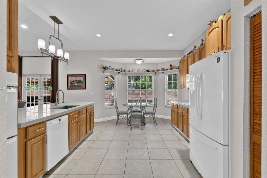 Kitchen featuring light-finish cabinetry, neutral tile flooring, beautiful quartzite countertops and a charming breakfast nook with lots of windows *