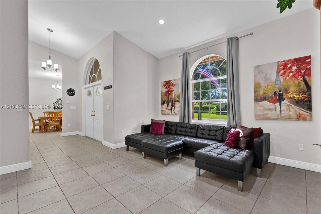 View of the formal living room and double door at the front foyer * natural lighting coiming in from the large arched windows, even above the front door.