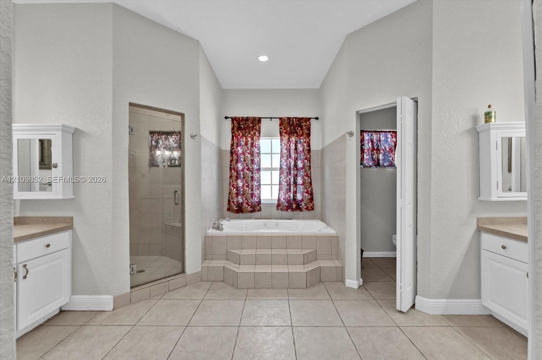 Soaking/spa tub with a separate glass-enclosed shower designed with multi high powered water jets, and dual vanities *