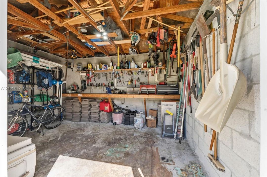CBS shed with brand new tiled roof, equipped with electricity, exposed wood truss ceiling, and a built-in wooden workbench *