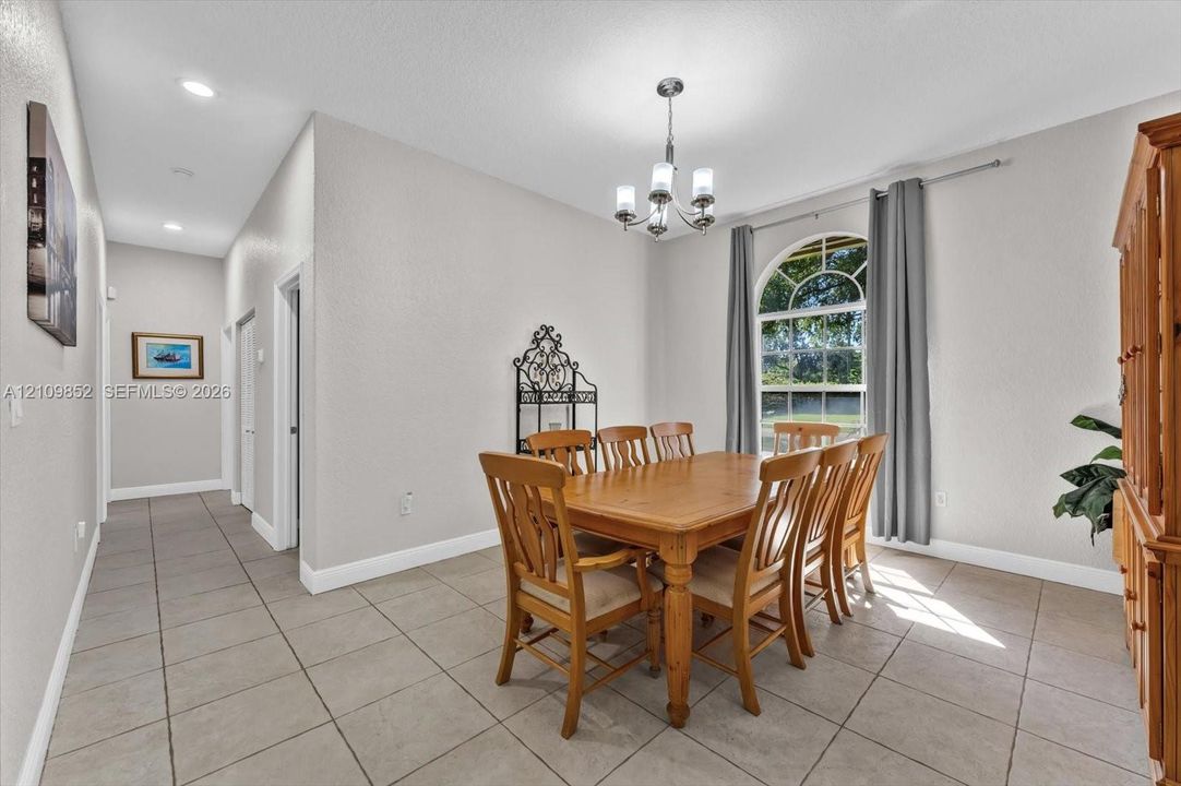 Neutral-toned interior featuring ceramic tile flooring, an arched window with decorative muntins, and a multi-arm chandelier