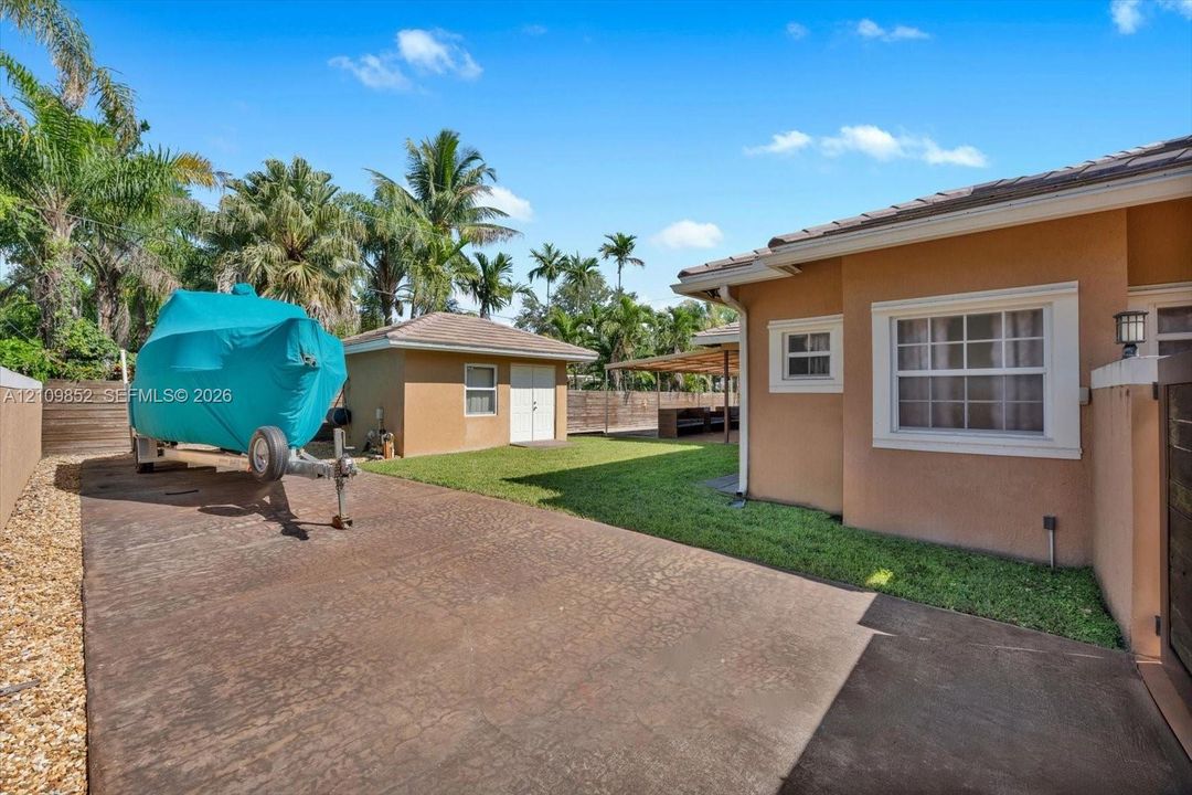 Extended concrete driveway in the back yard perfect for RV, Boat or extra car storage * View of the detached CBS shed in the background * Concrete wall on the side *