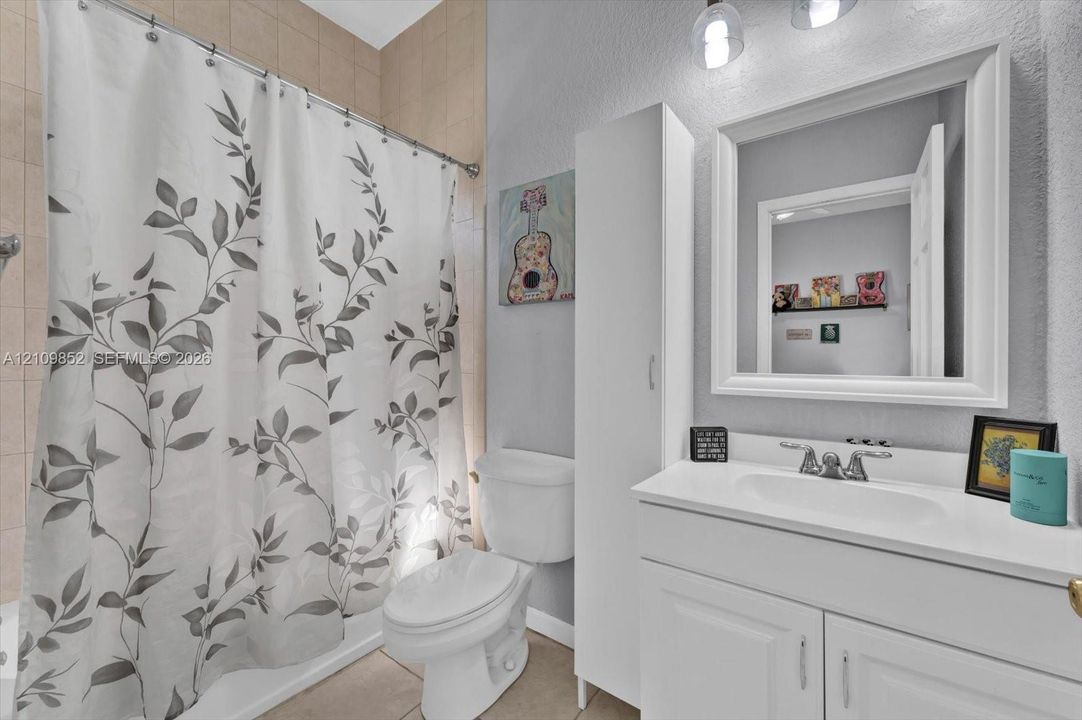 Ensuite bathroom featuring a vanity with an integrated countertop sink, tall storage cabinetry, framed wall mirror, and a combination tub/shower *