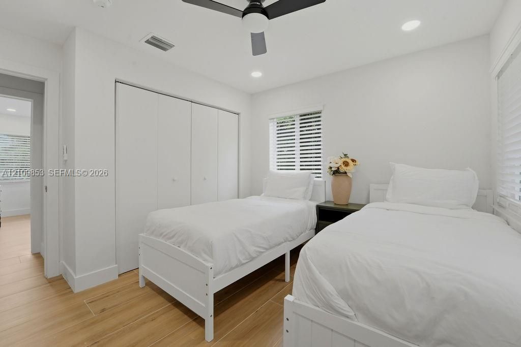 Room featuring wood-finish flooring, recessed lighting, a modern ceiling fan, and built-in closet storage