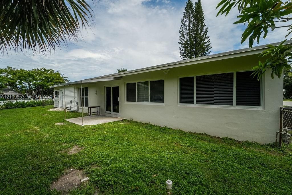 Exterior rear facade featuring a concrete patio, sliding glass doors, white siding, and horizontal windows