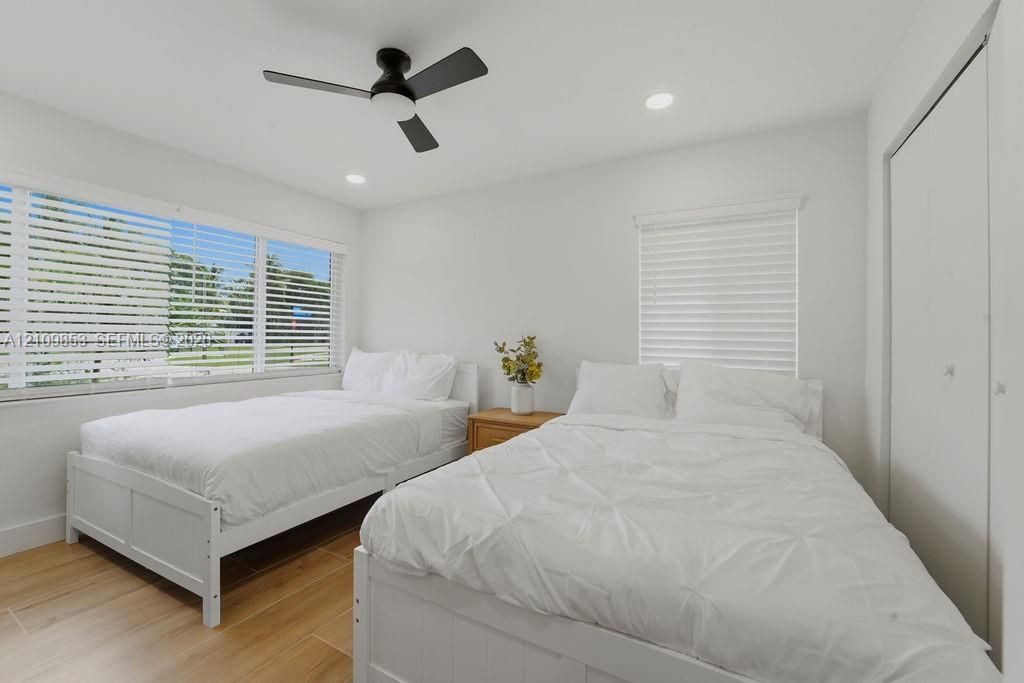 Bedroom featuring wood-finish tile flooring, recessed lighting, matte black ceiling fan, and horizontal window blinds