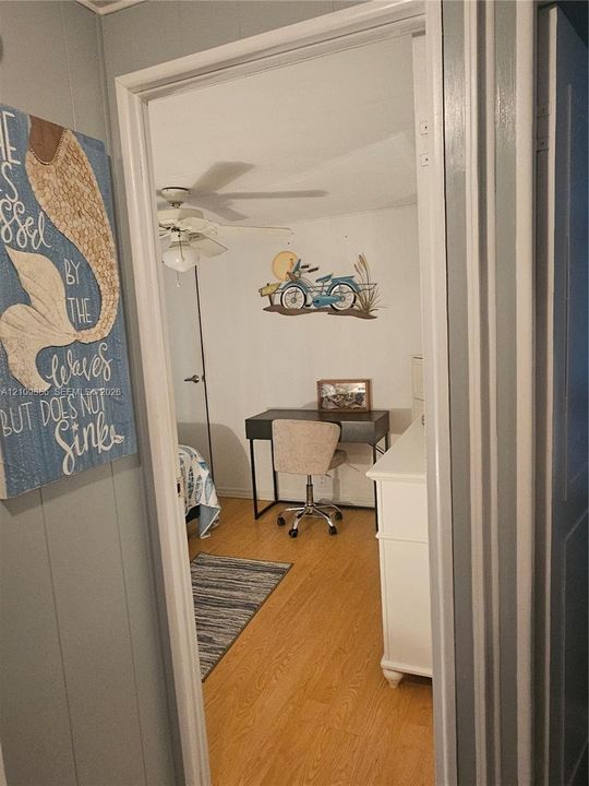 Interior space featuring wood-finish flooring and a white ceiling fan with integrated lighting