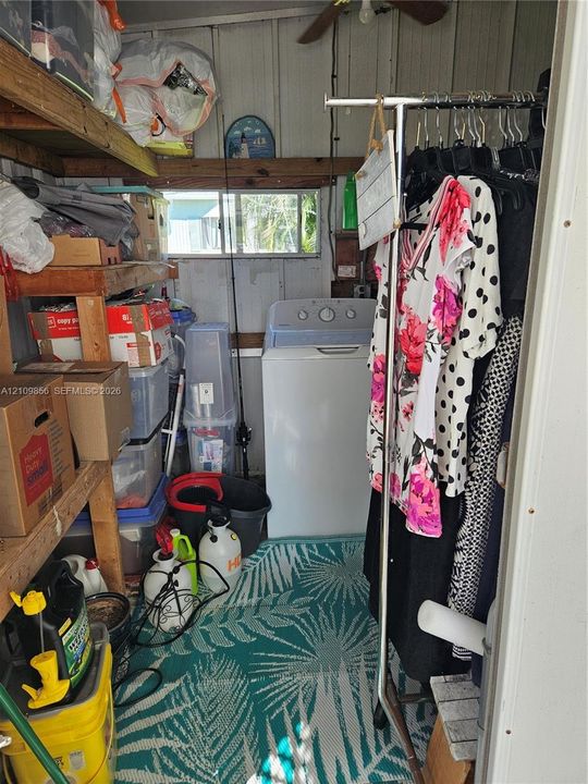 Utility space featuring wooden wall paneling, built-in wooden shelving, a horizontal window, and a ceiling-mounted fan