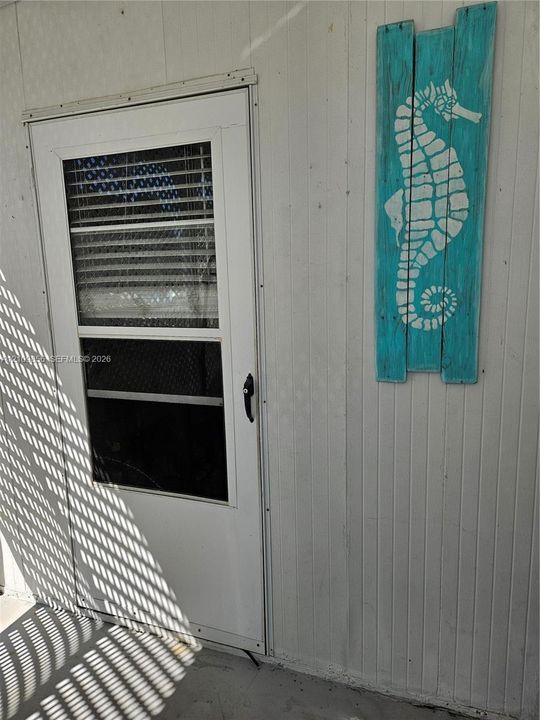 White metal storm door with integrated screen and vertical paneled exterior siding