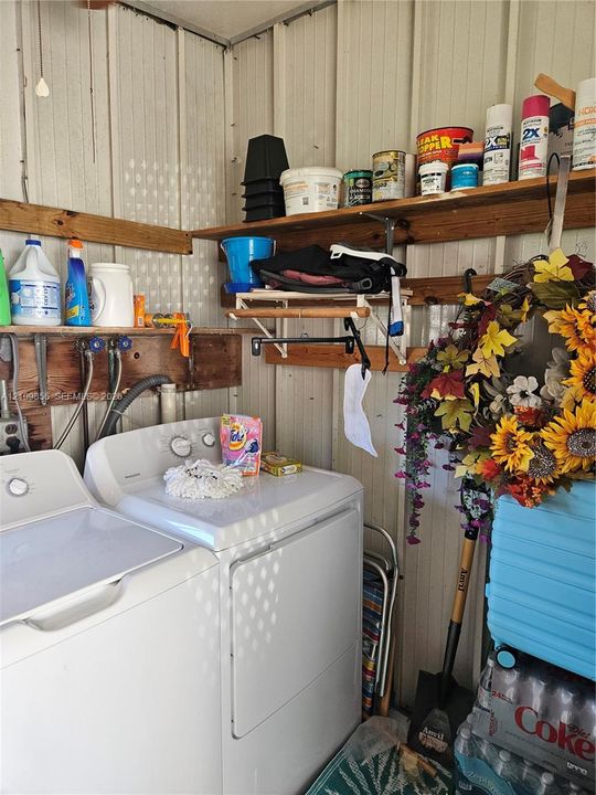 Utility area featuring metal panel wall construction, integrated laundry hookups, and wooden wall-mounted shelving