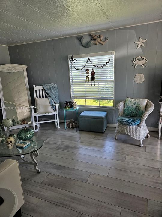 Wood-finish flooring and a single-pane horizontal sliding window featuring horizontal blinds