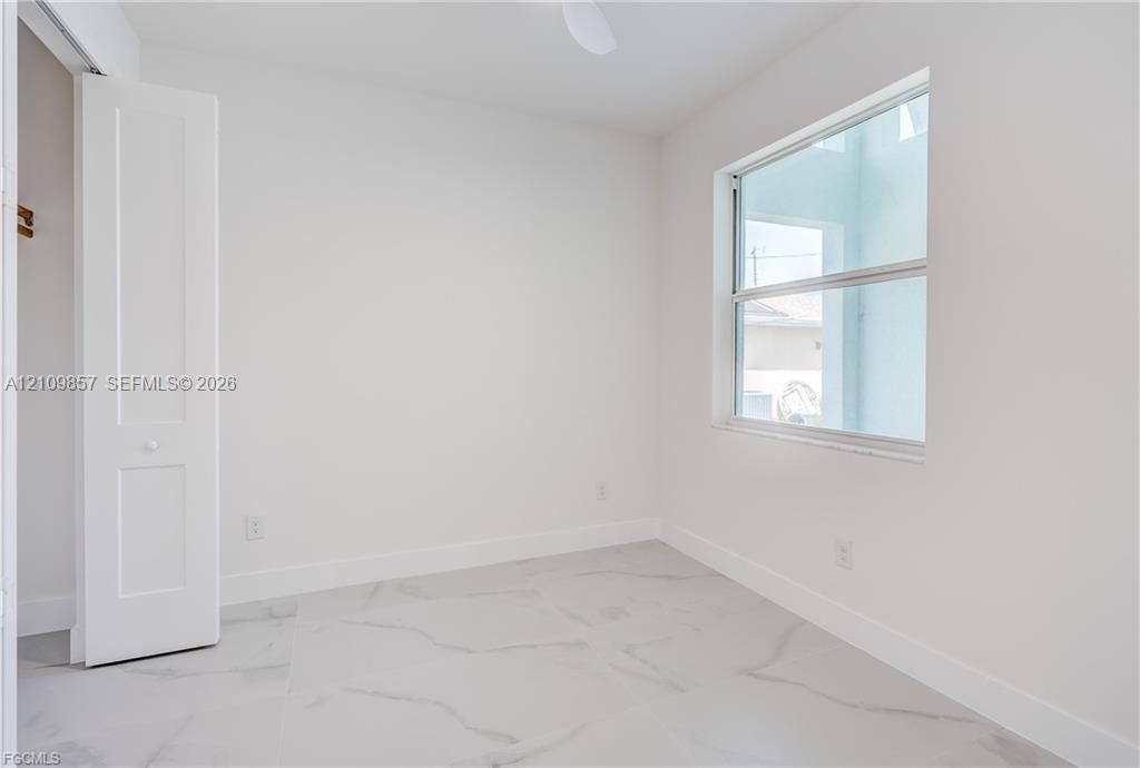 Room featuring large-format tile flooring, bright neutral walls, a single-hung window, and a built-in closet with double-panel doors