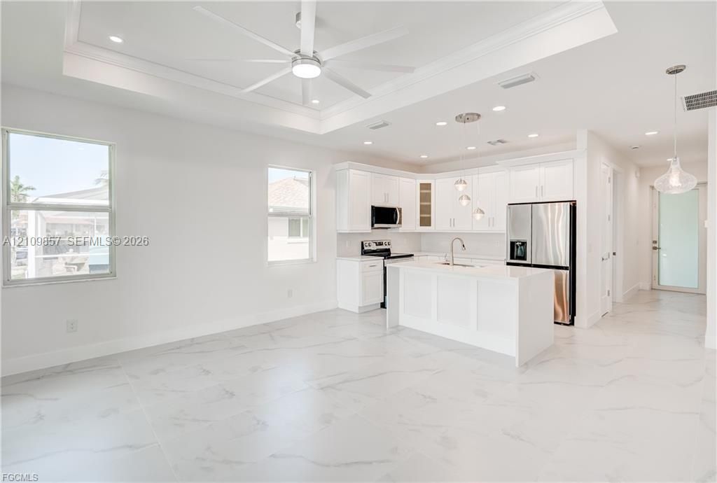 Kitchen featuring white cabinetry, an island with stone-finish countertops, recessed lighting, a tray ceiling with a center fan, and polished tile flooring