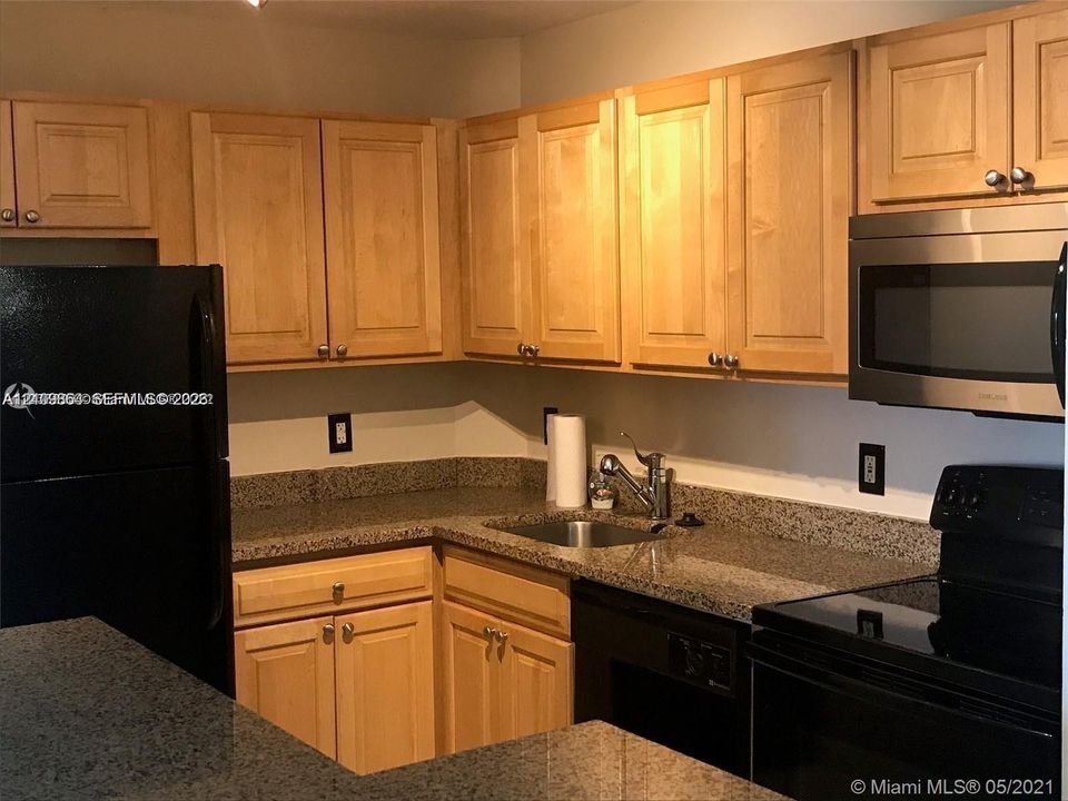 Kitchen featuring shaker-style wood cabinetry, stone countertops, stainless steel undermount sink, and integrated stainless steel microwave