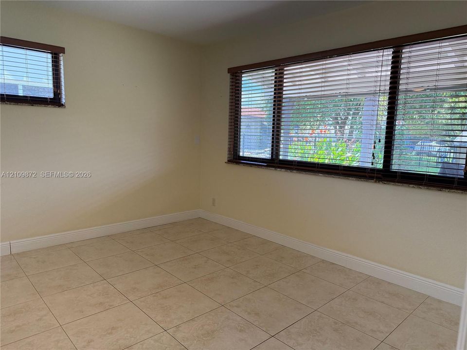 Room featuring neutral wall finishes, tile flooring, and windows with horizontal blinds