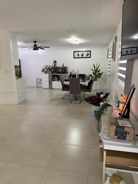Large-format neutral tile flooring throughout featuring a matte finish, recessed lighting, and a modern ceiling fan
