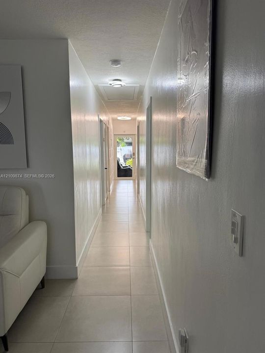 Hallway featuring neutral-toned tile flooring, recessed ceiling lighting, and smooth-finish walls