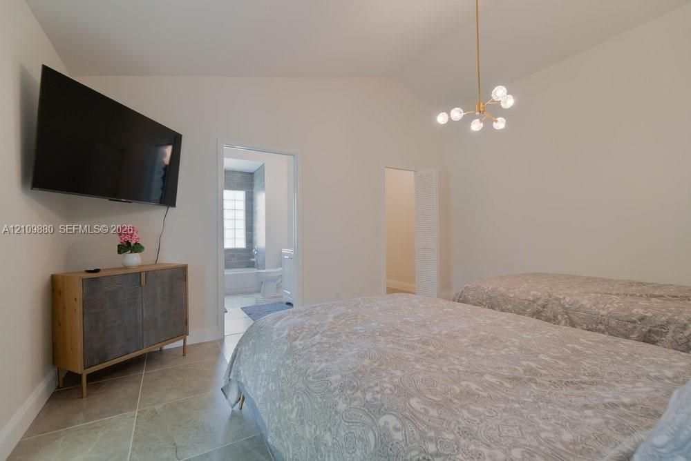 Vaulted ceilings, large-format tile flooring, and a contemporary multi-arm brass chandelier