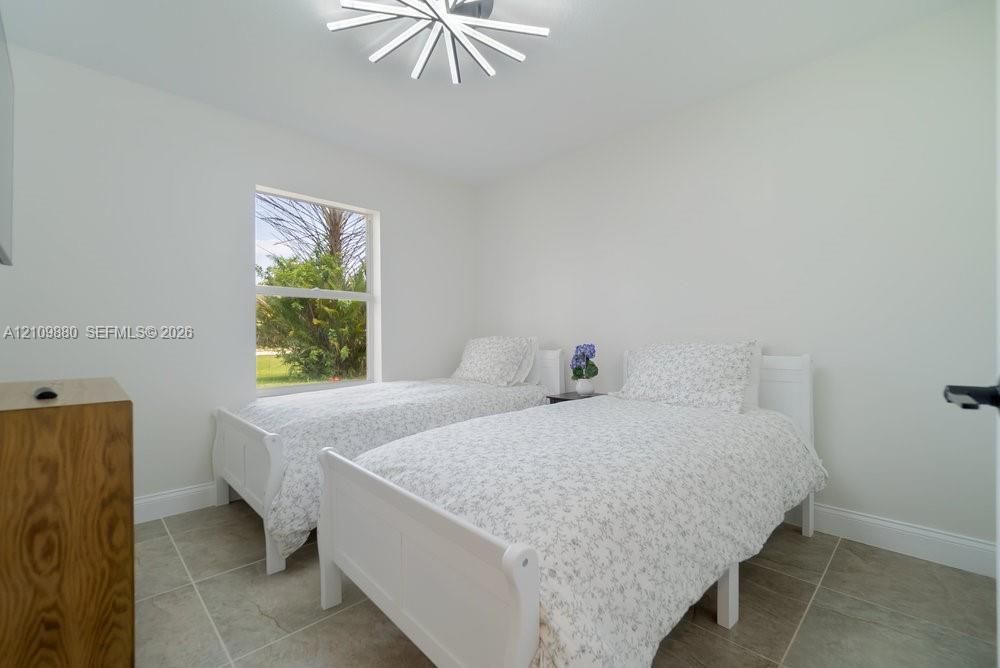 Neutral-toned room featuring large-format ceramic tile flooring, a geometric LED ceiling fixture, and a single-pane window