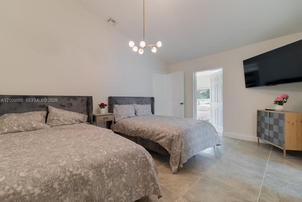 Vaulted ceiling featuring a modern multi-globe chandelier and large-format tile flooring