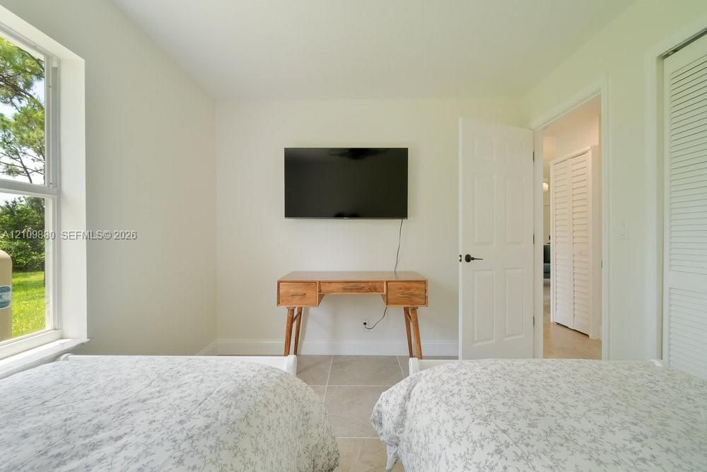 Neutral-toned interior featuring large windows, neutral floor tile, and white louvered closet doors