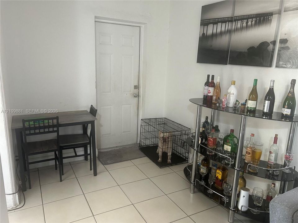 Neutral-toned ceramic tile flooring throughout the room with a single-panel interior entry door featuring brushed nickel hardware