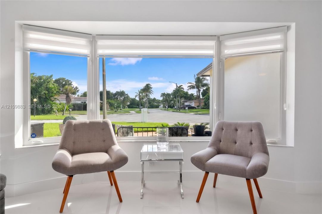 Large bay window featuring crisp white framing, integrated roller shades, and neutral polished flooring