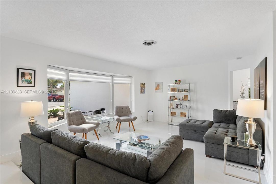 Expansive living space featuring neutral wall finishes, polished tile flooring, and a large bay window