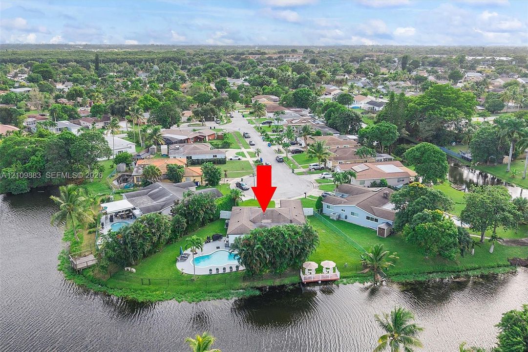 Waterfront property featuring a private swimming pool, concrete patio, dock, and extensive perimeter landscaping