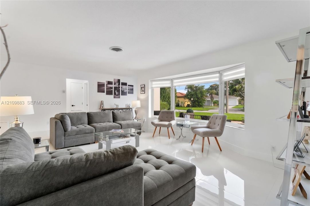 Living area featuring polished tile flooring, expansive bay window, and crisp white wall finishes