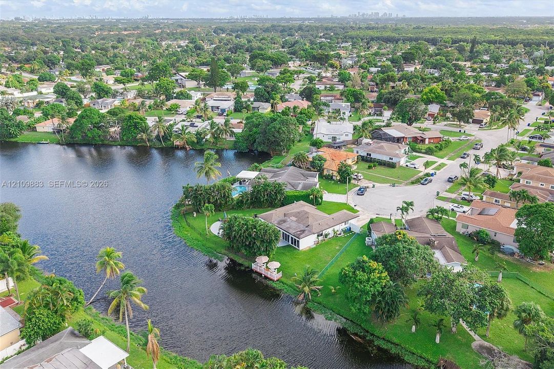 Waterfront property featuring a private dock, expansive lawn, mature palm trees, and an in-ground swimming pool